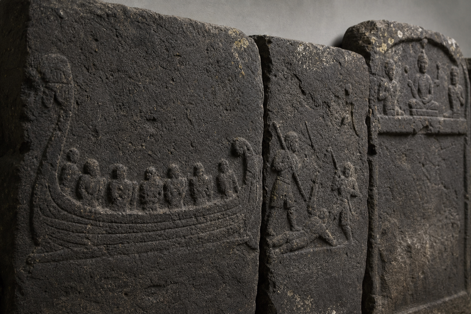 Close view of weathered hero-stone reliefs showing a boat, armed figures, a fallen figure, and an upper sacred panel.