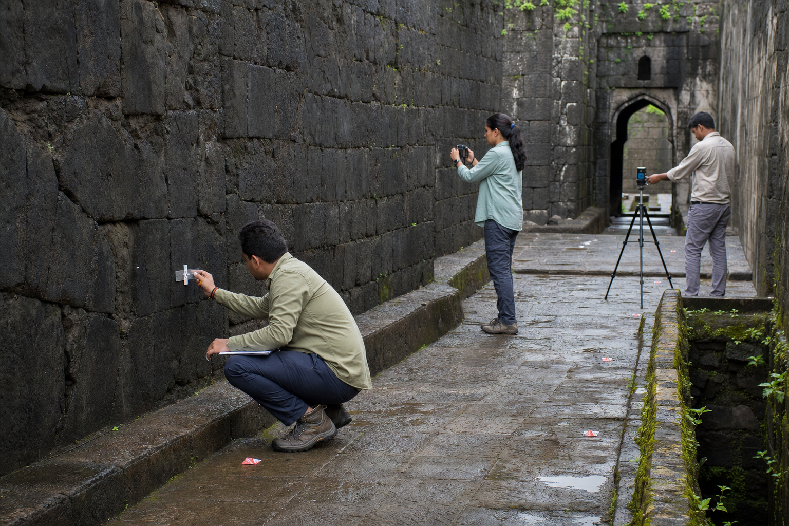 Heritage engineers use non-invasive instruments to examine cracks, masonry joints, drainage, and pedestrian movement in a stone passage at Vishalgad.