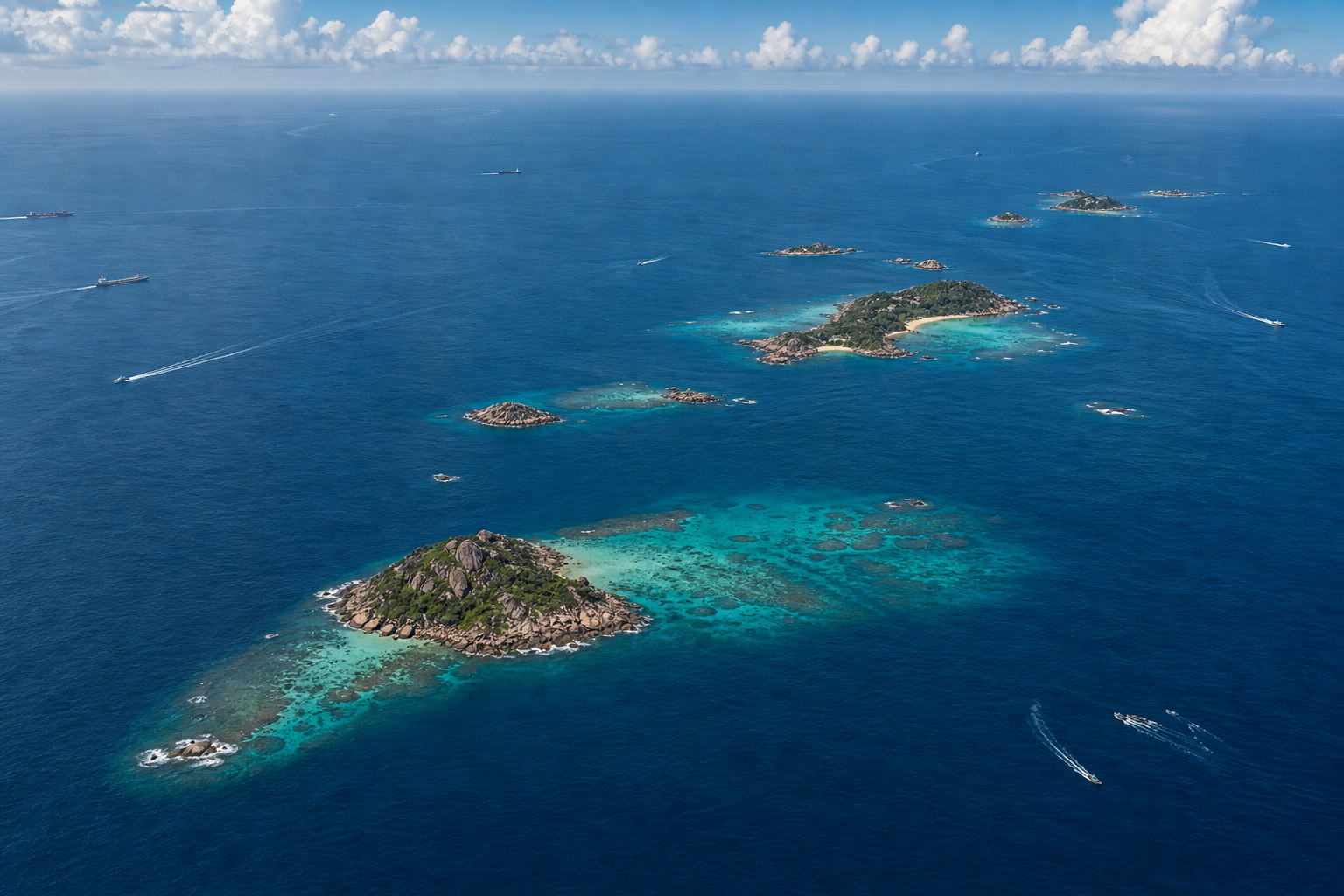 Small tropical islands and coral reefs sit within a vast ocean crossed by several distant vessels.