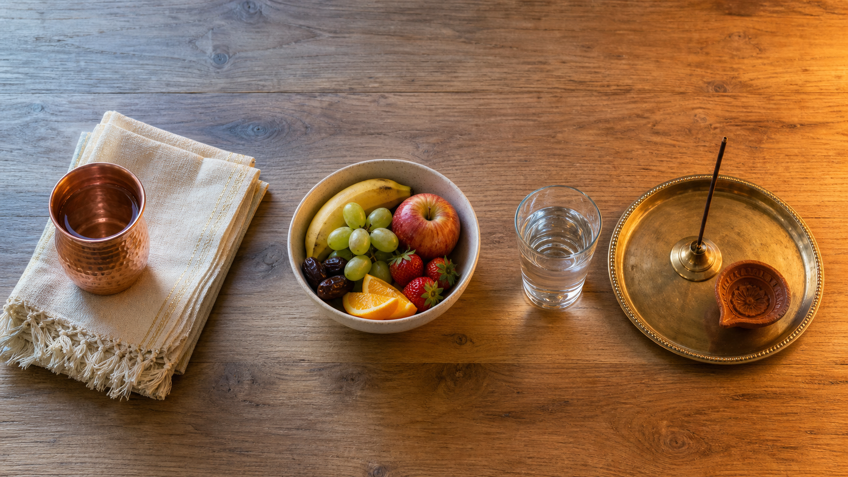 An overhead arrangement of morning water, daytime fruit, and an evening puja tray representing three stages of a fasting day.