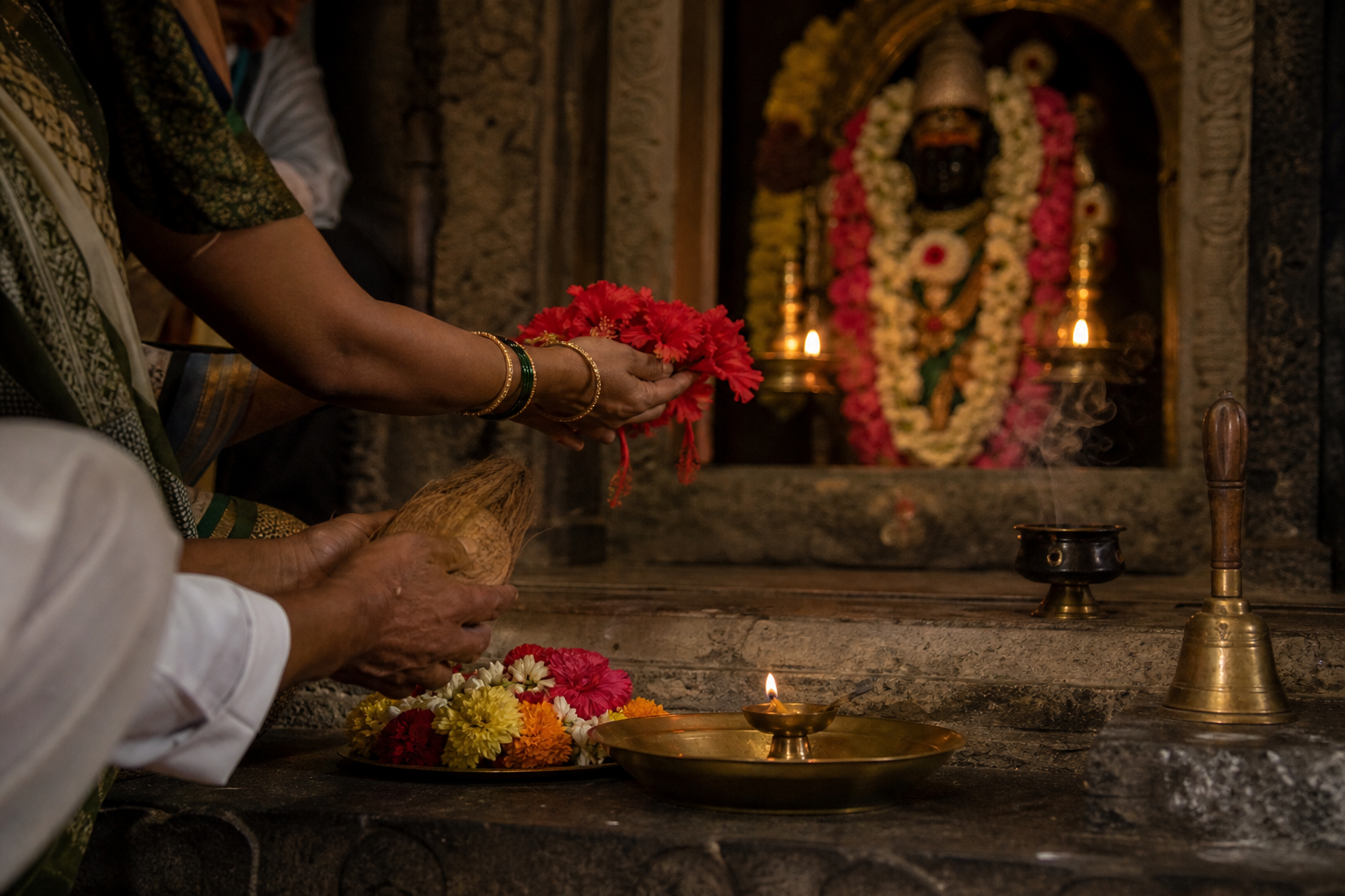 Pilgrims place flowers, a coconut, and a small oil lamp before a softly lit goddess shrine.