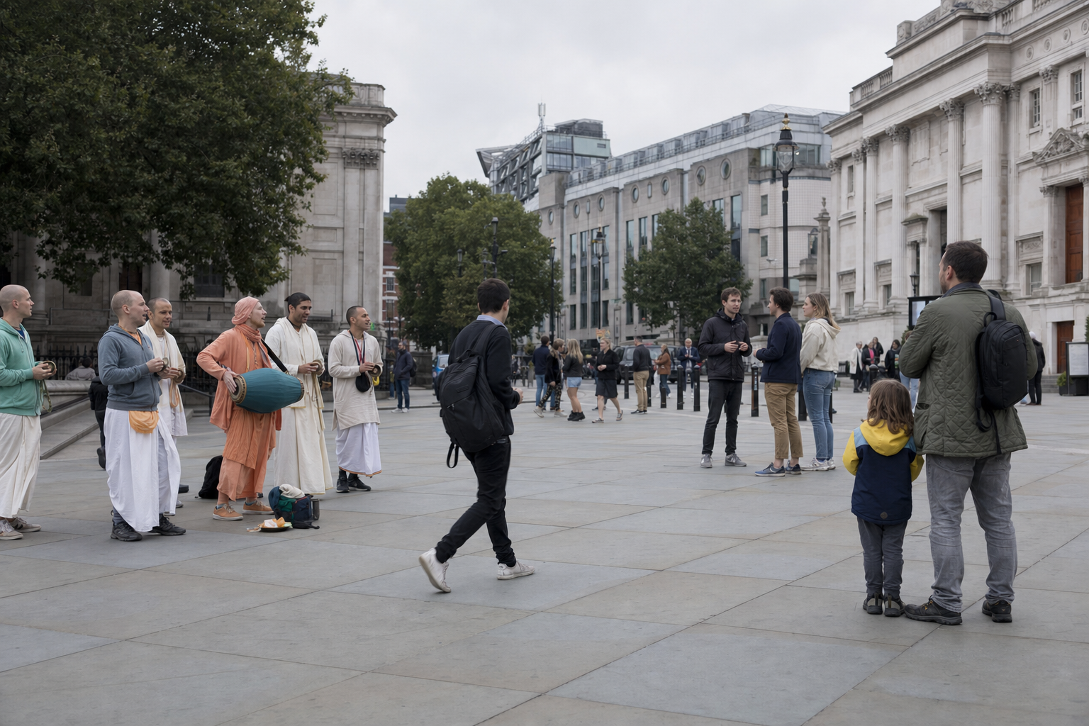 A Hare Krishna group chants in a London square while some pedestrians pause and others continue on their way.