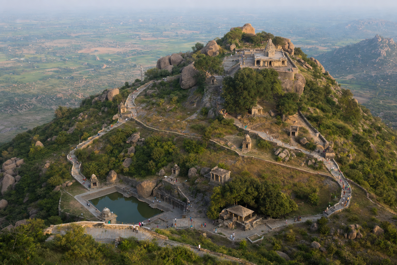 An elevated view shows pilgrims following paths among a hilltop temple, smaller shrines, stone pavilions, and a sacred water tank.