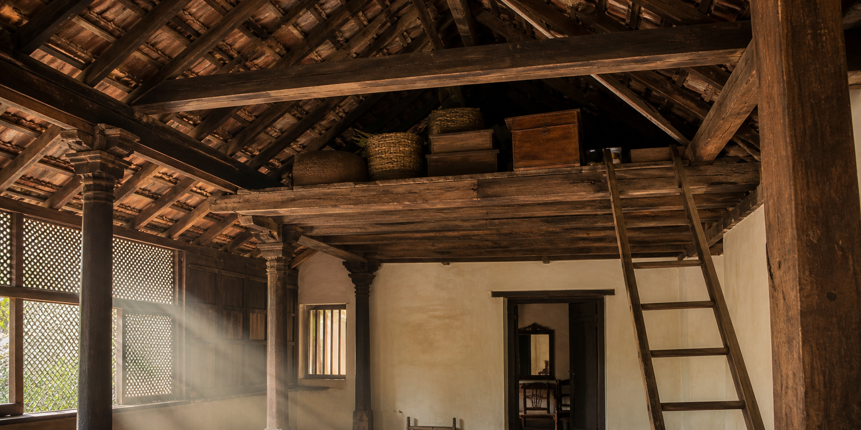 Wooden loft, rafters, roof tiles, and access ladder inside an old Kerala ancestral house.