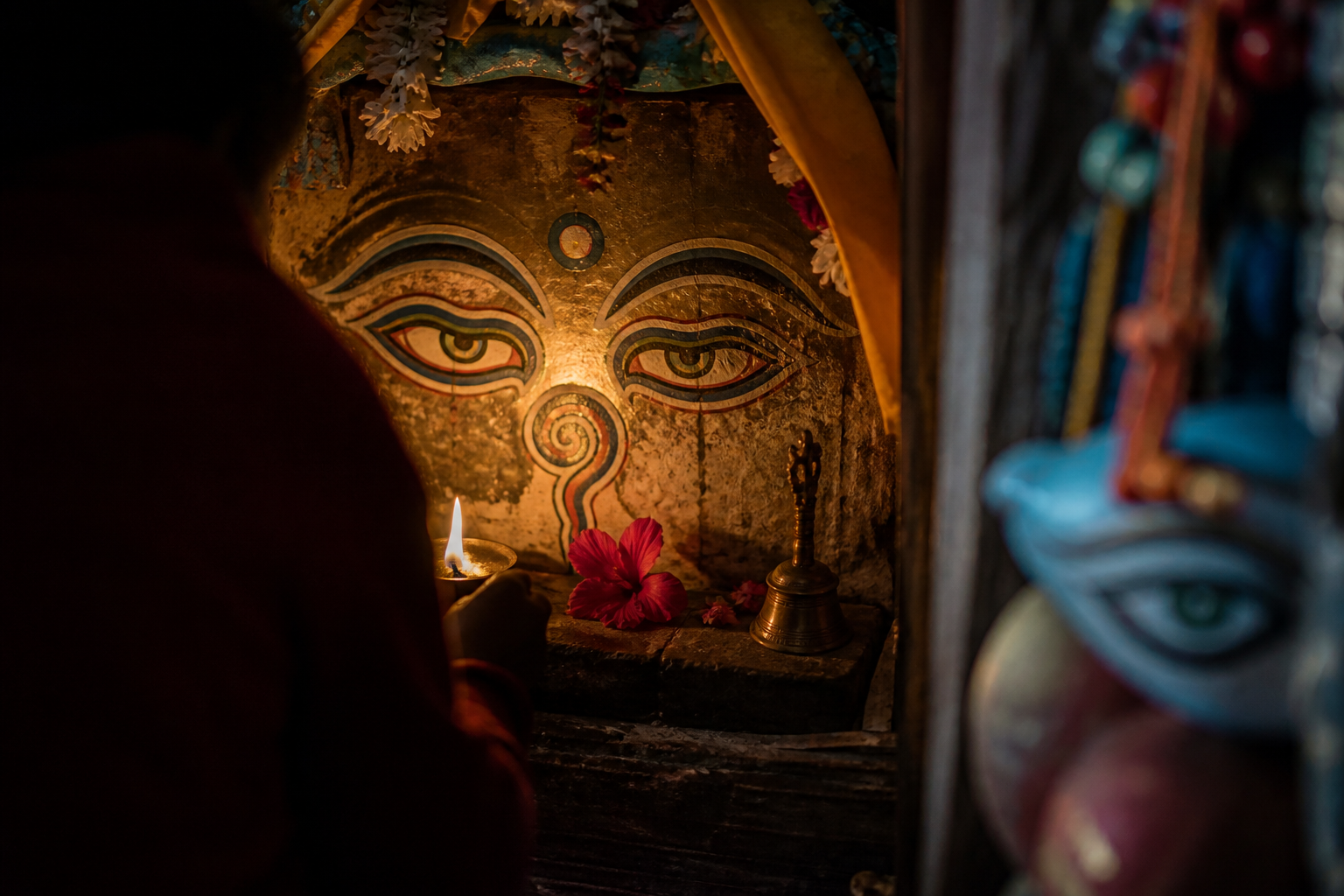 Painted sacred eyes glow within an active shrine while an isolated decorative eye motif remains blurred at the edge of the scene.
