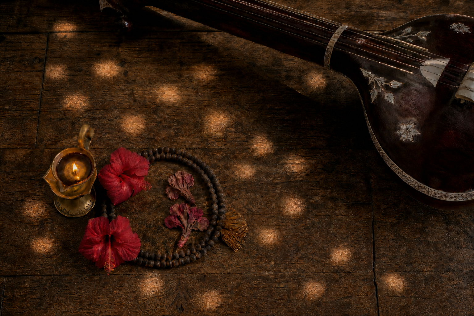 A brass lamp, prayer beads, hibiscus flowers and the shadow of a tanpura form a quiet devotional still life in morning light.
