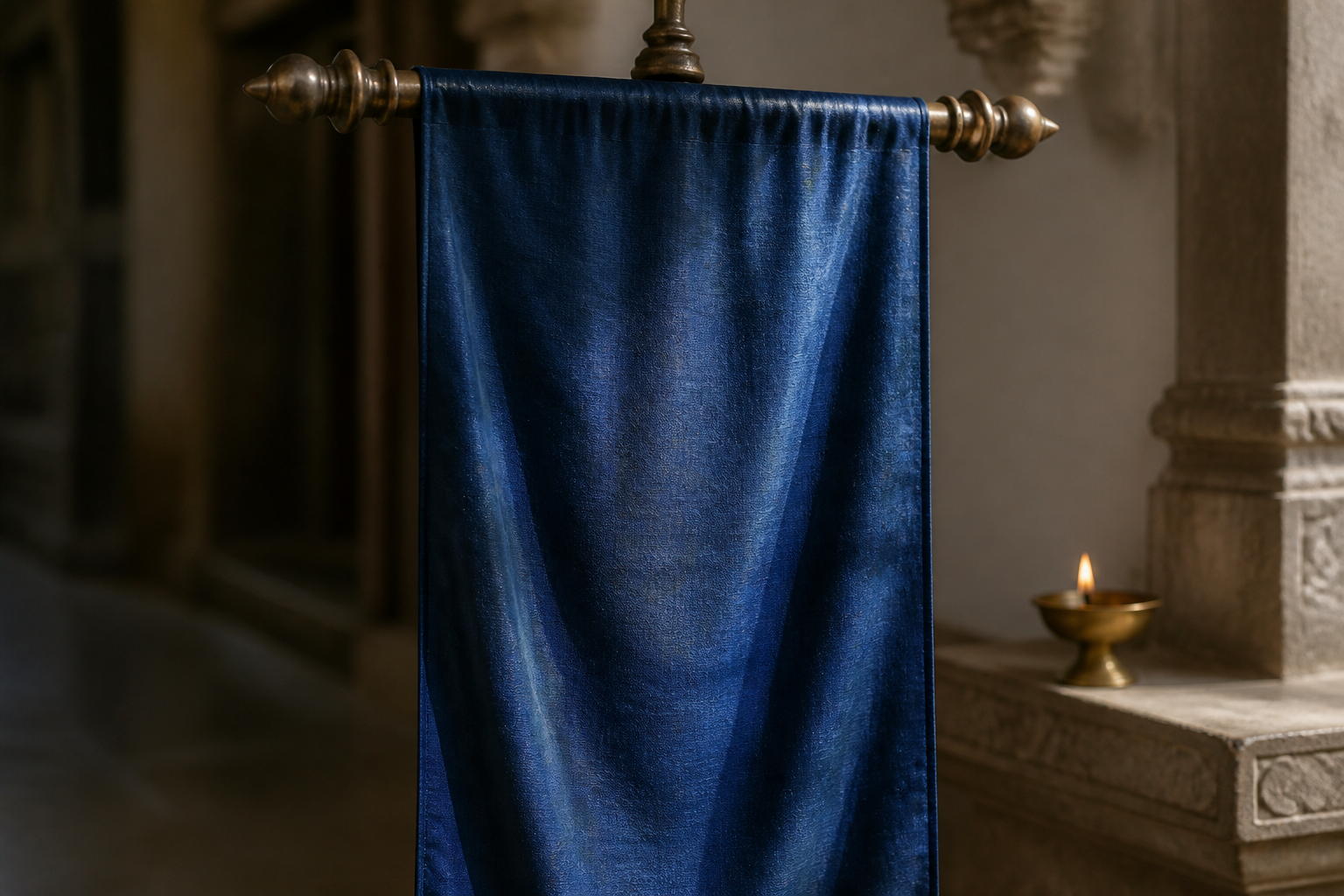 An unmarked indigo ceremonial banner hangs from a bronze finial in a softly lit stone temple passage.