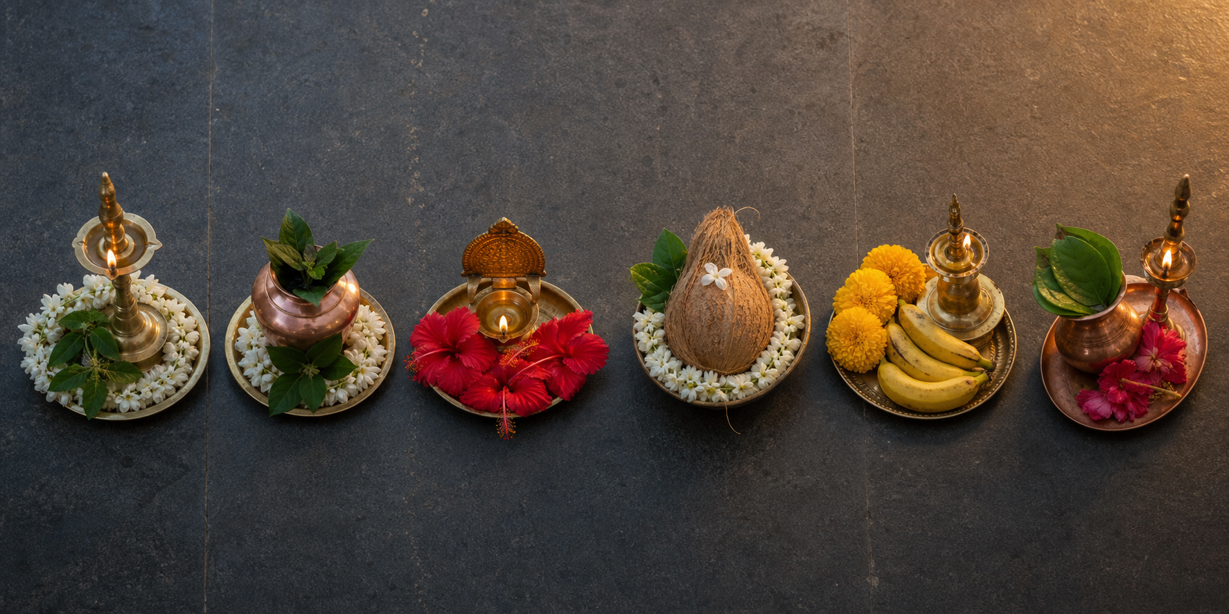 Six small South Indian ritual arrangements with lamps, flowers, sacred leaves, fruit and copper vessels laid in a row on dark stone.