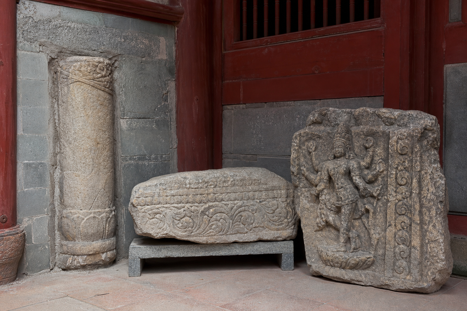 Reused carved granite elements with South Indian-derived reliefs are set into later architecture in a Chinese Buddhist temple courtyard.