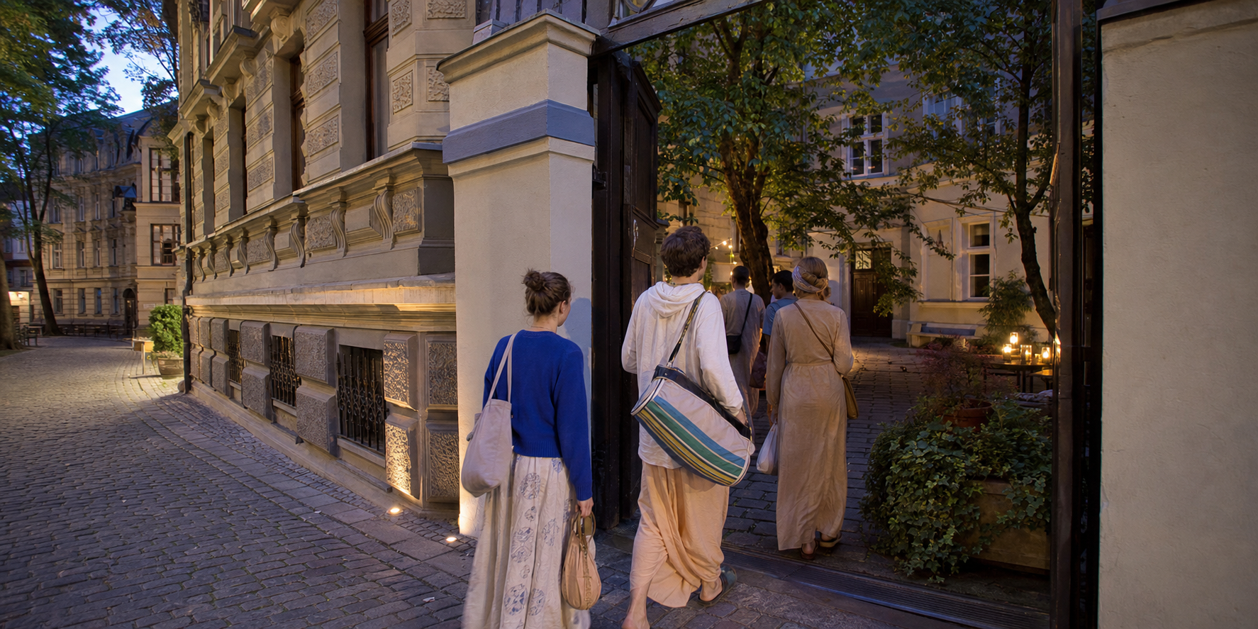 A small group carrying kirtan instruments walks through a Riga courtyard surrounded by Art Nouveau buildings on a summer evening.