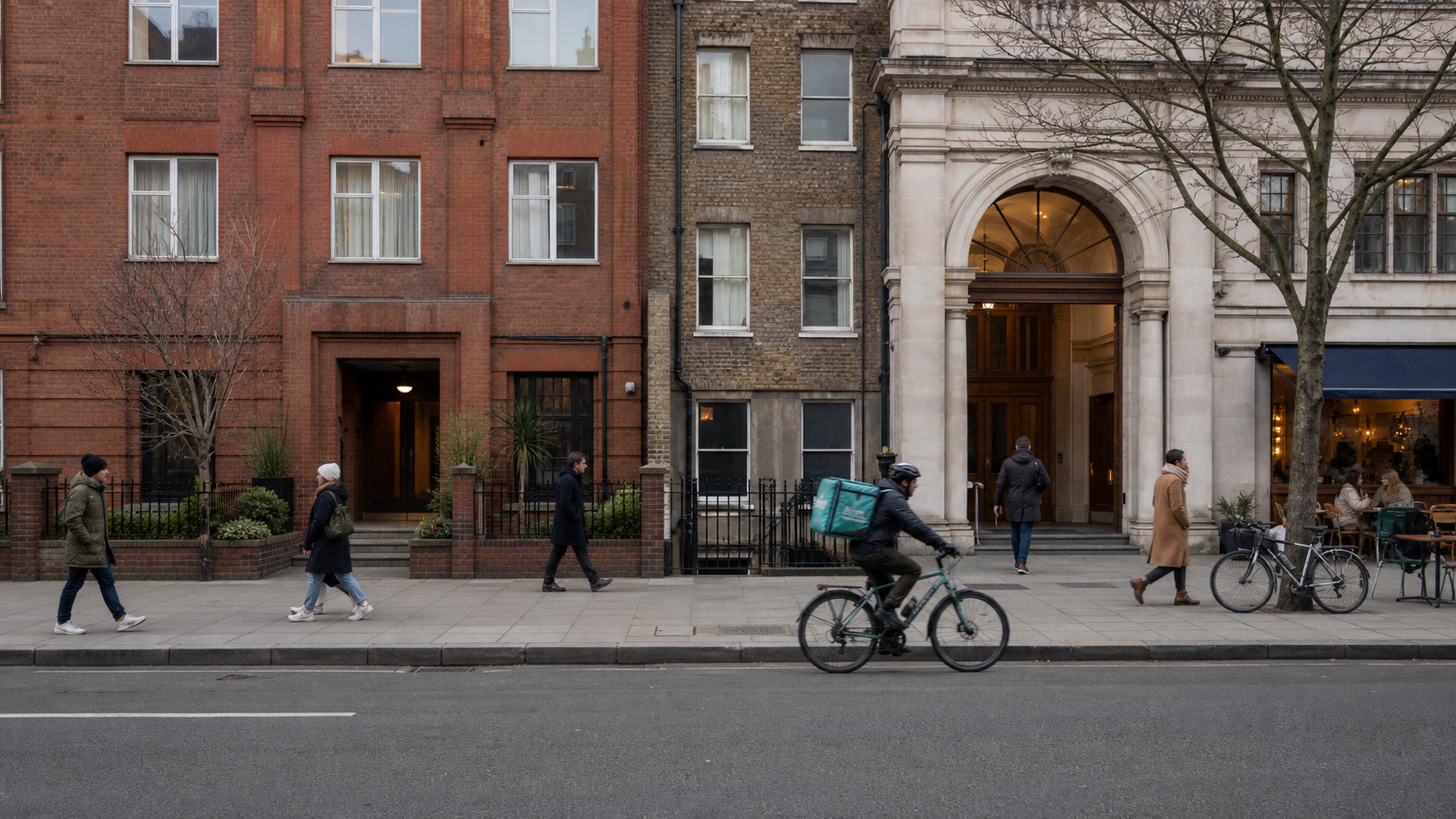 Two architecturally distinct community buildings share a Bloomsbury block with pedestrians, a cyclist, bicycles and residential windows.