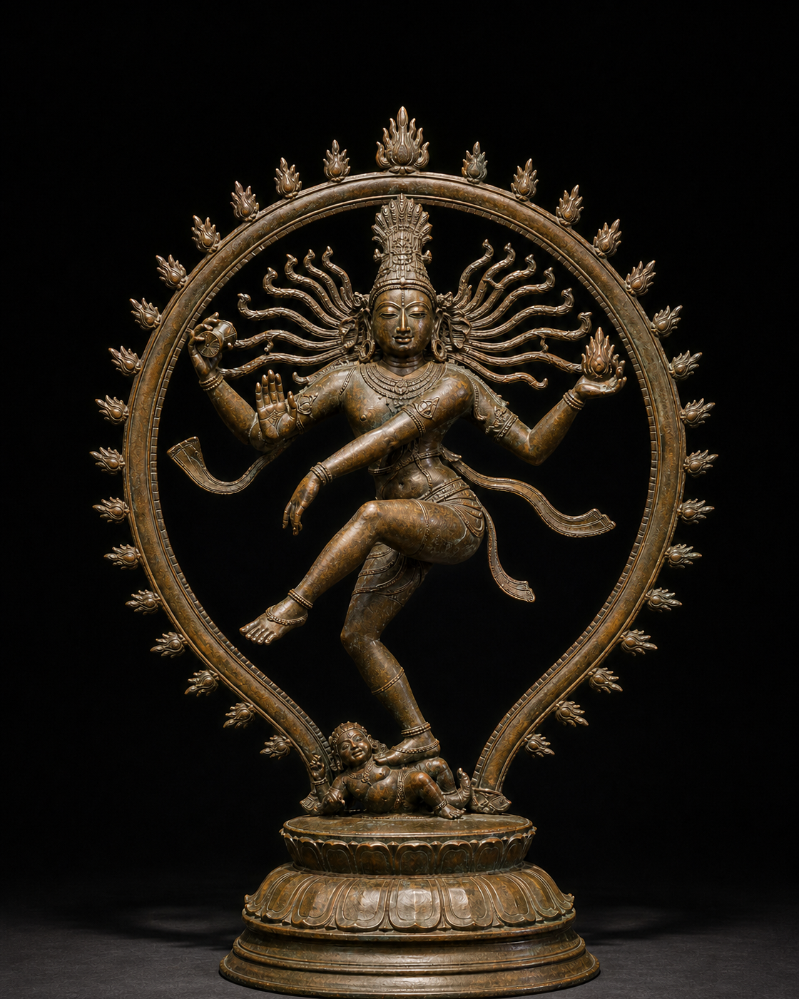 A Chola-style bronze Nataraja dances within a ring of flames, holding a drum and fire, raising one hand in assurance, lifting one foot, and standing on a dwarf figure.