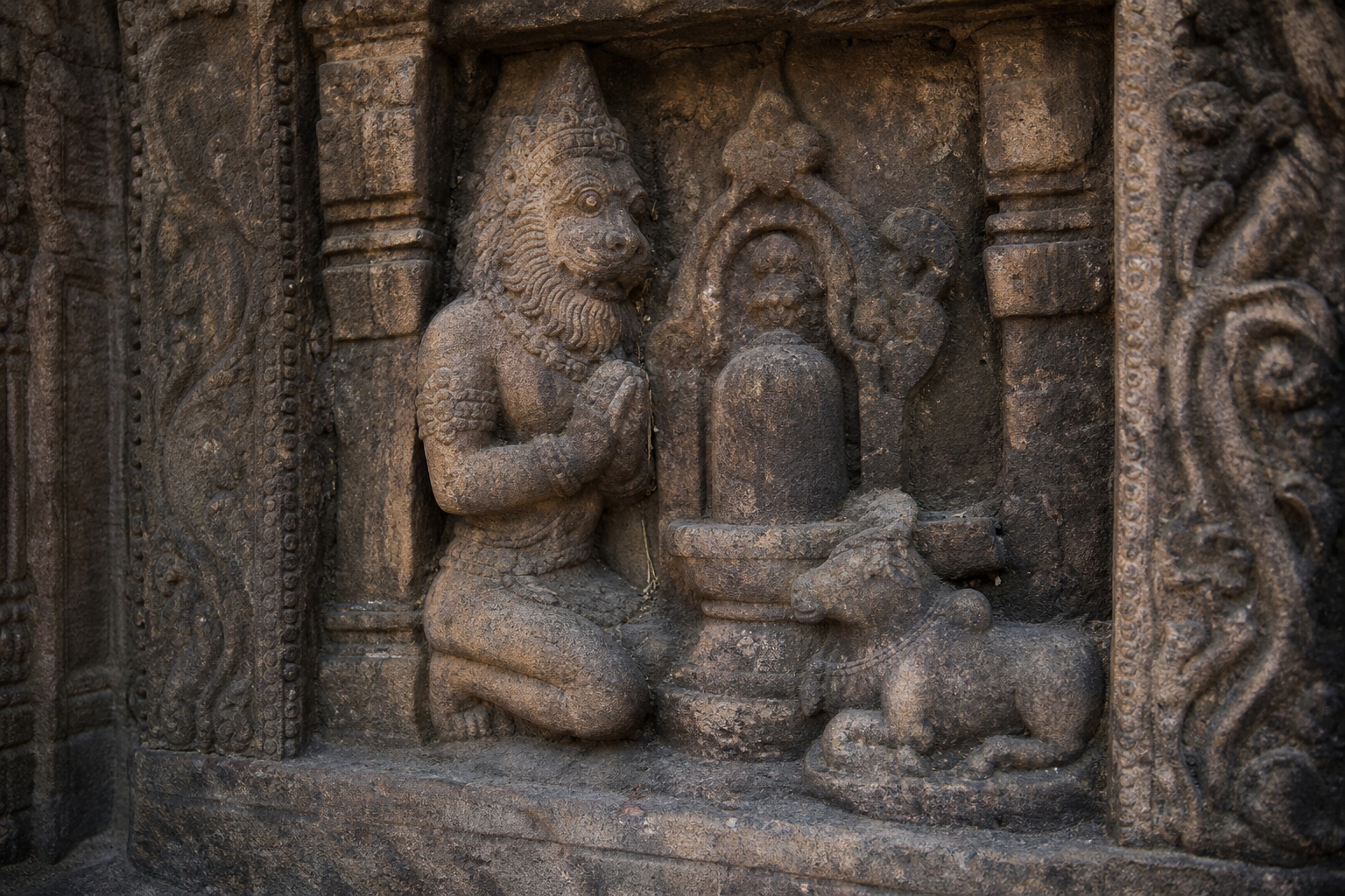 Weathered stone relief at Singhanath Temple showing the lion-headed Narasimha in a reverential devotional posture within a Shiva shrine.