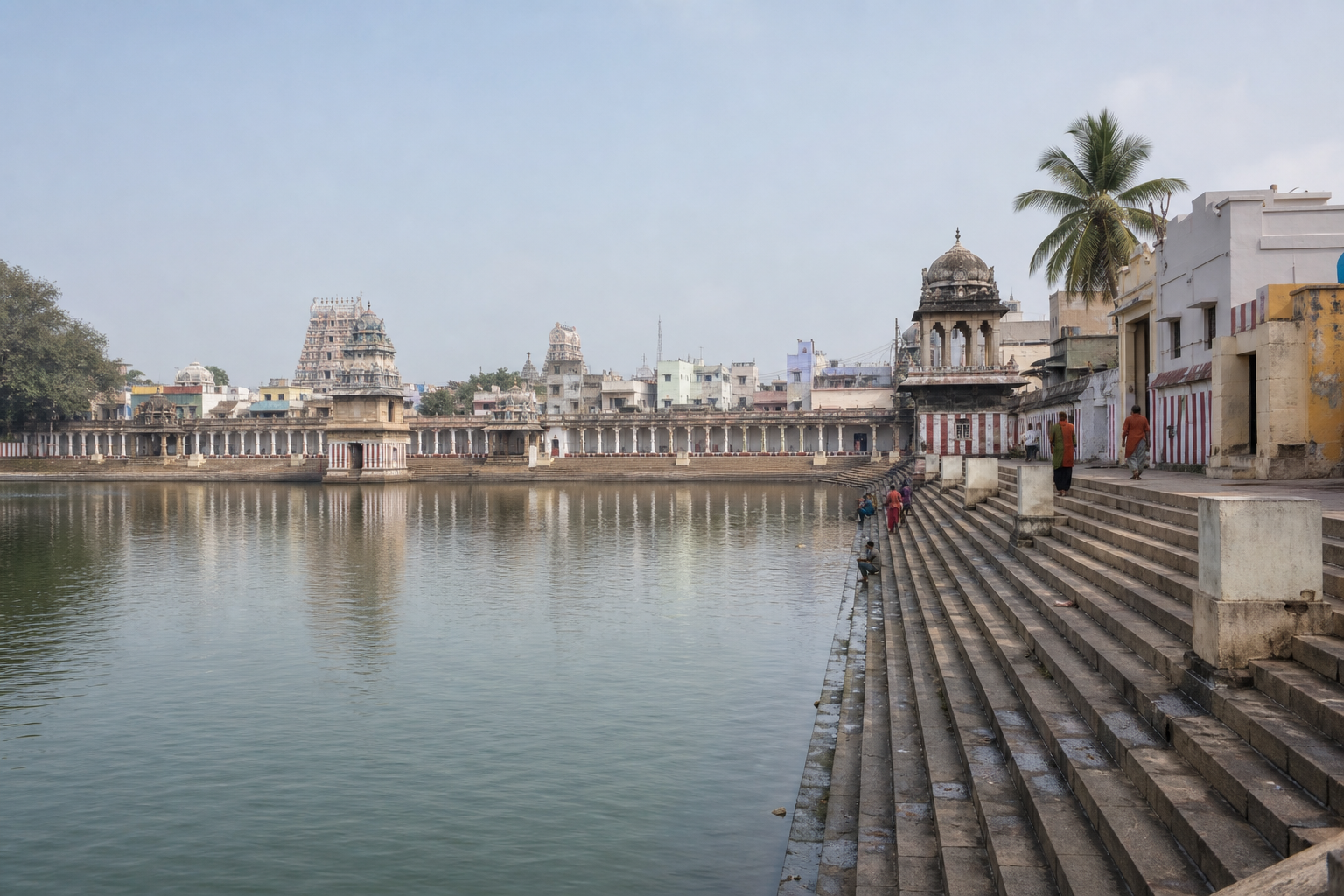 Mahamaham Tank with broad stone steps, water, temple architecture, and the surrounding Kumbakonam townscape.