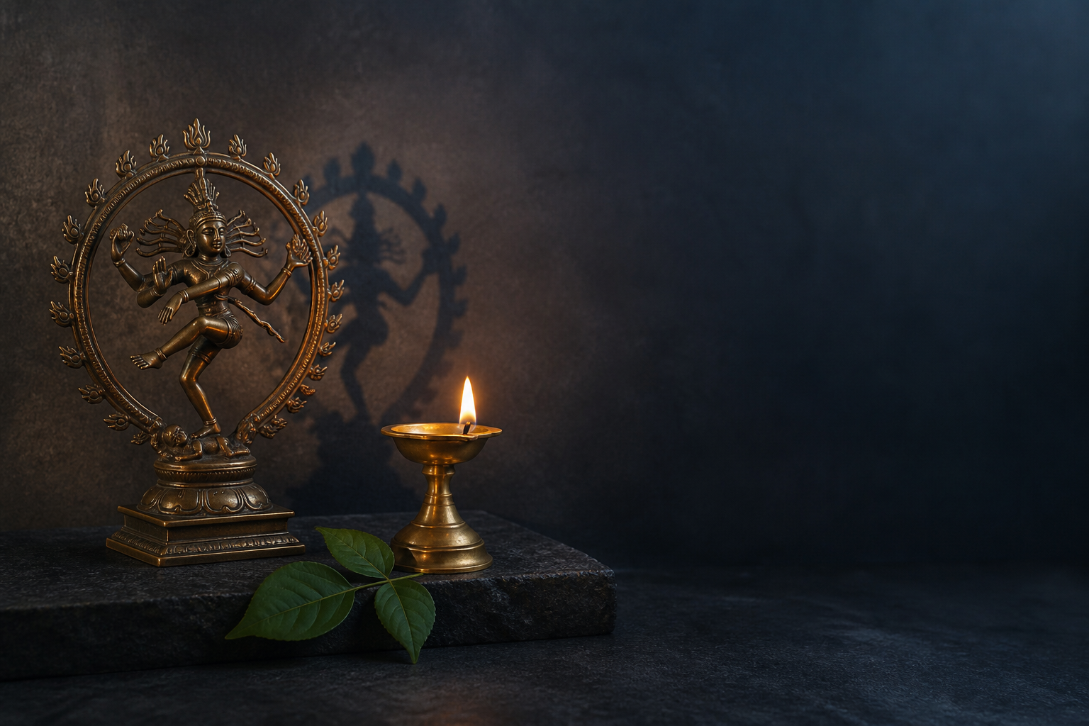 A small bronze Nataraja, a brass oil lamp, and bilva leaves rest beside an open area on a dark stone surface.