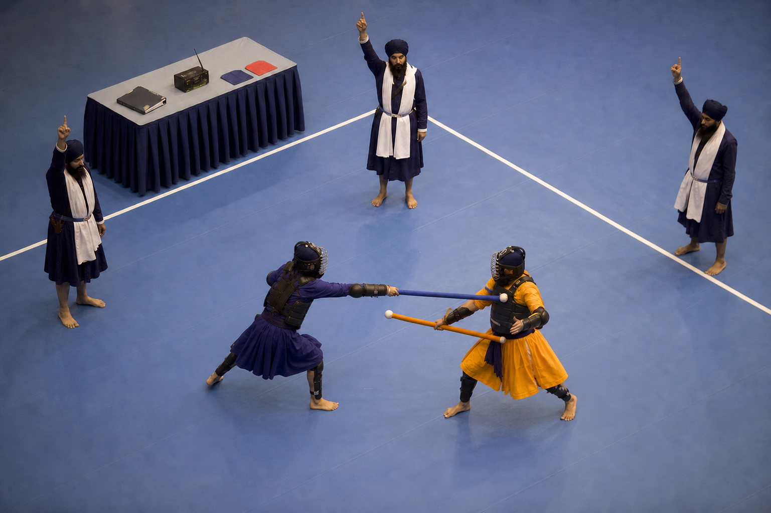 Three officials observe the same close Gatka exchange near a boundary line and make matching hand signals.