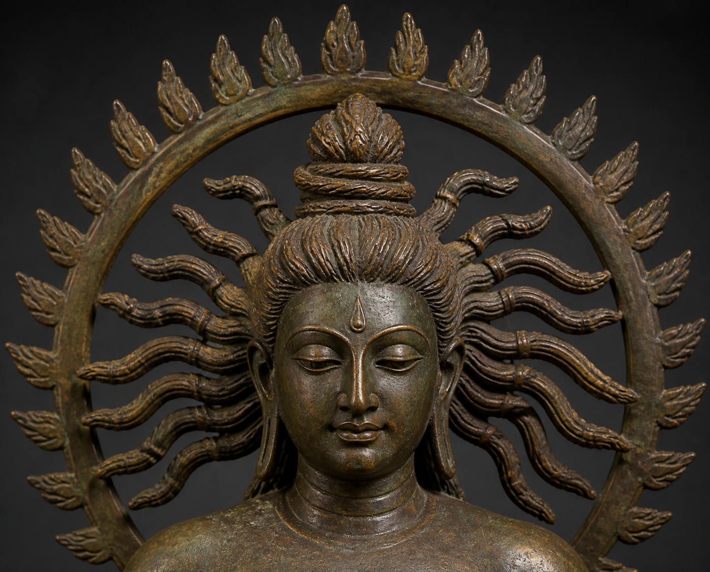 Close view of a bronze-style Shiva head showing individual matted locks, crown hair, and a separate circular aureole behind them.