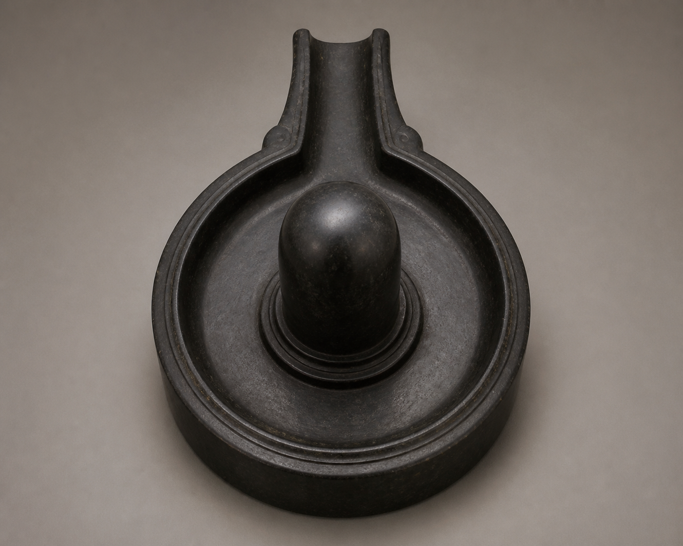 Overhead view of a stone Shivling showing the rounded Linga, oval Gauripatta base, and the base's projecting drainage outlet.