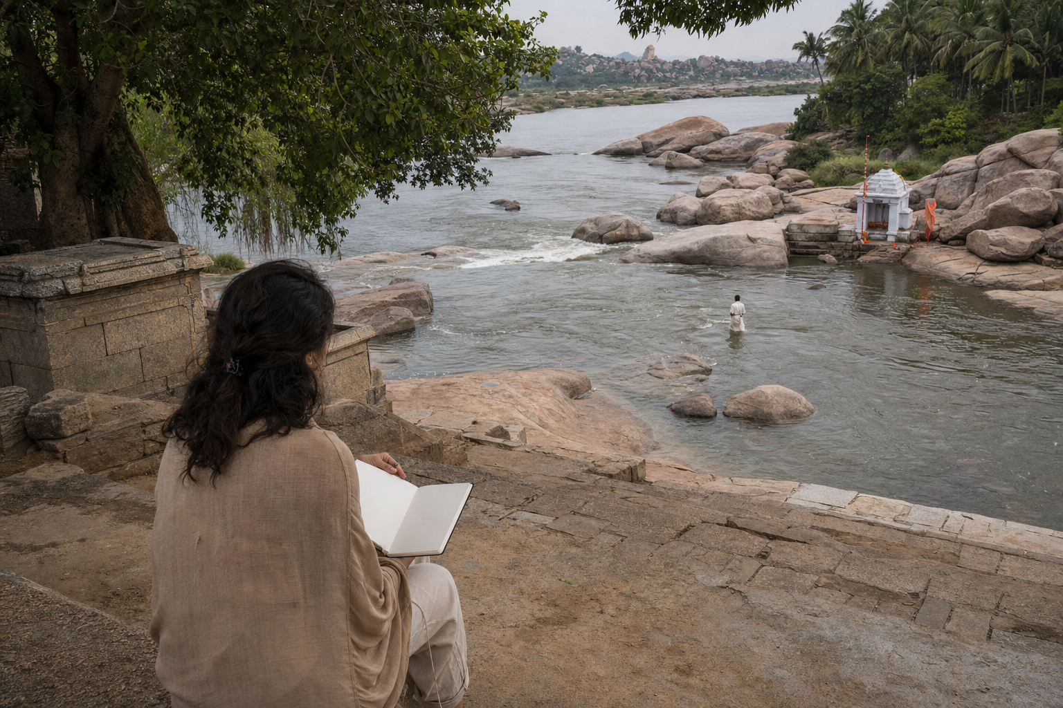 A visitor with a blank notebook pauses on stone steps overlooking the Tungabhadra River and a small shrine at Chakratirtha.
