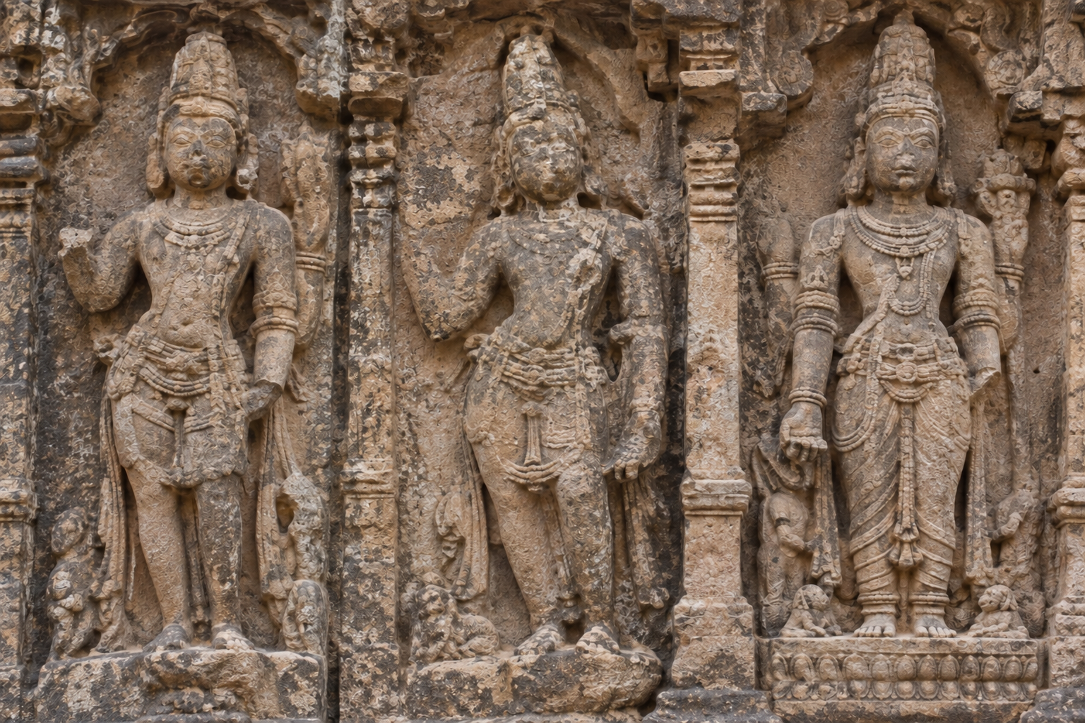 Three adjacent temple figures show broken attributes, eroded shapes, mineral staining, and other ambiguous surface details.