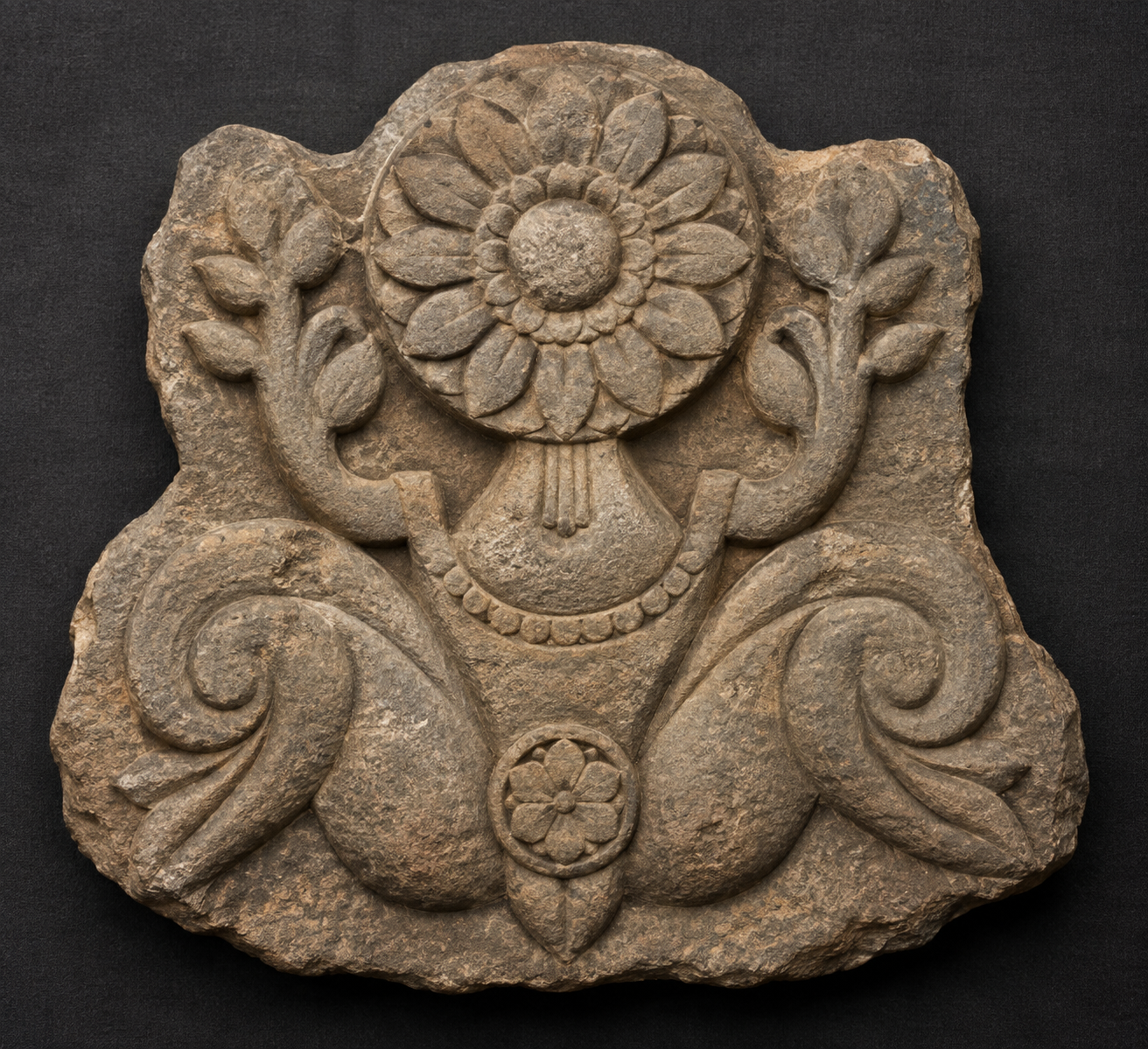 Overhead view of a symmetrical stone relief with raised arms, outward-bent knees, an exposed torso, and a many-petaled lotus in place of a face.