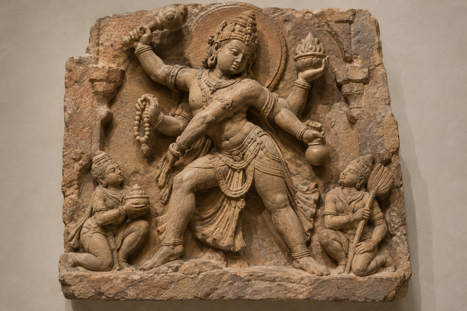 Full sandstone relief of a turning sacred figure with one hand poised for action and two smaller attendants nearby.