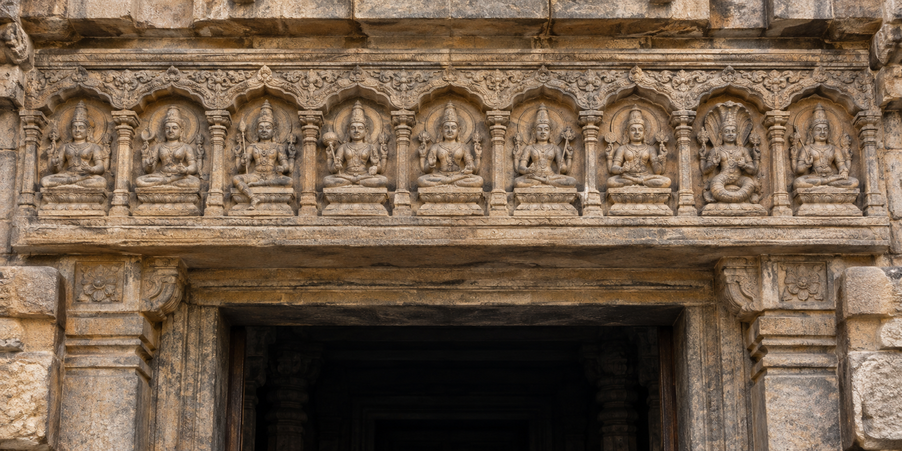 A complete nine-figure Navagraha panel carved above a shadowed temple doorway.