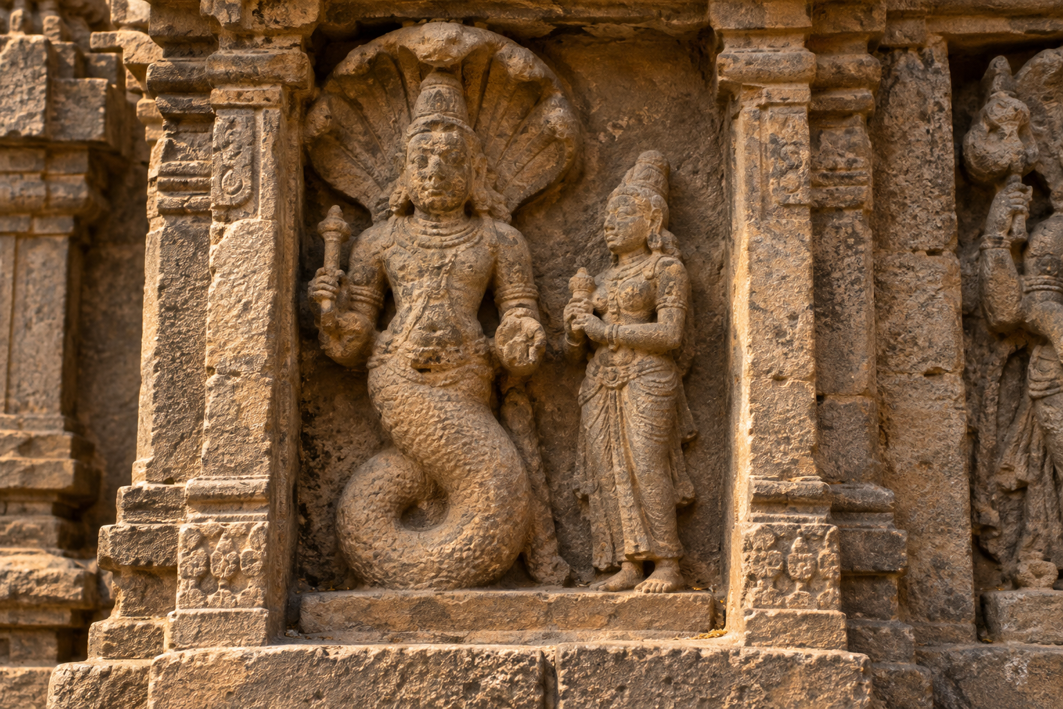 Ketu and a smaller standing companion carved within the same weathered stone niche, oriented toward one another on a shared base.