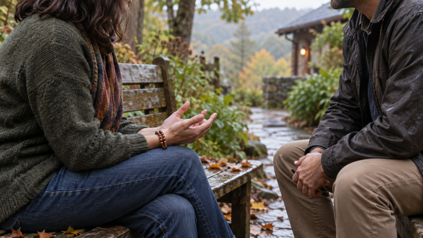 Two adults speak attentively on a garden bench, with wooden mantra beads resting around one participant's wrist.