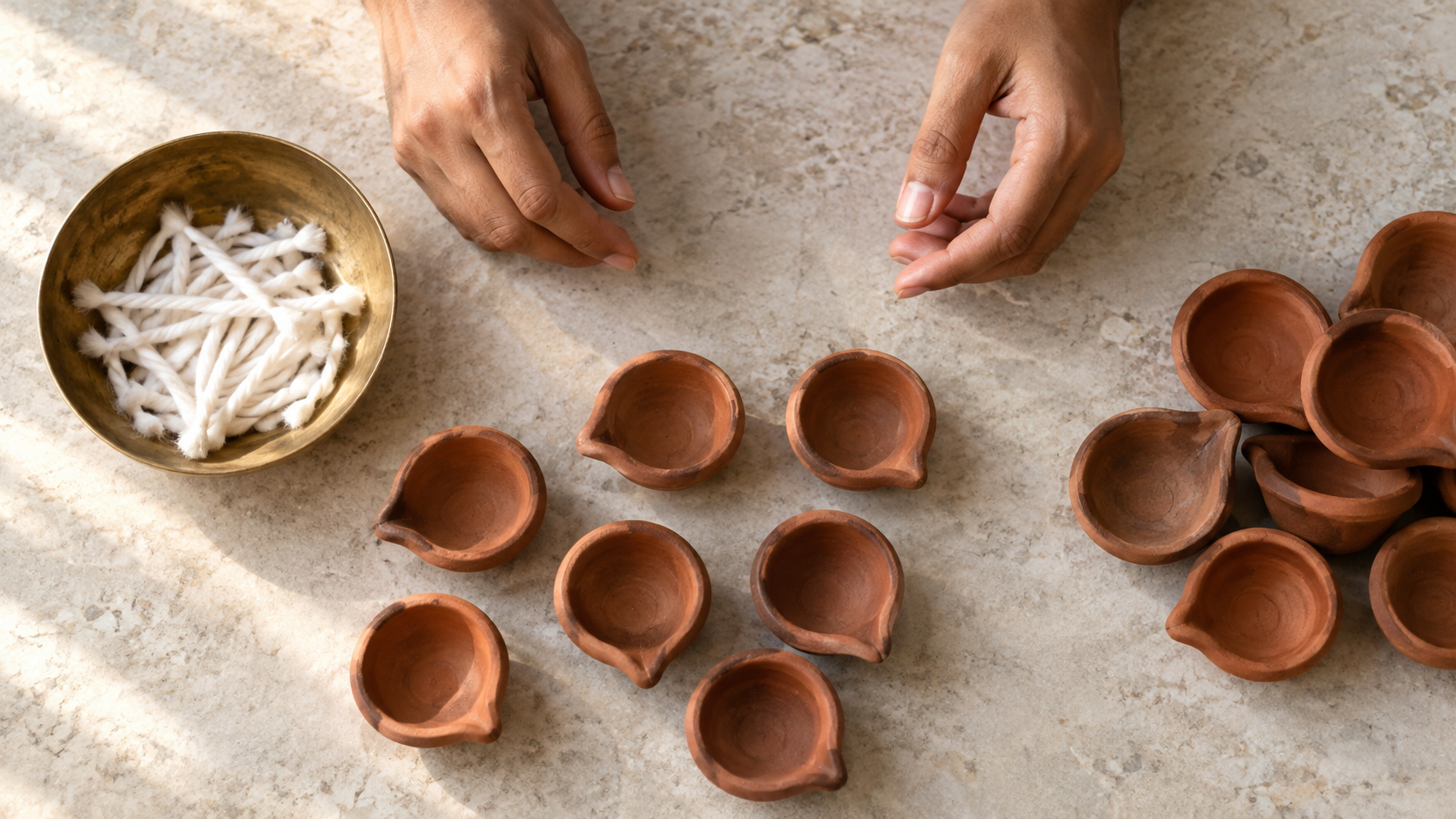 Grouped clay lamps and loose cotton wicks are arranged separately while a devotee prepares the offering.