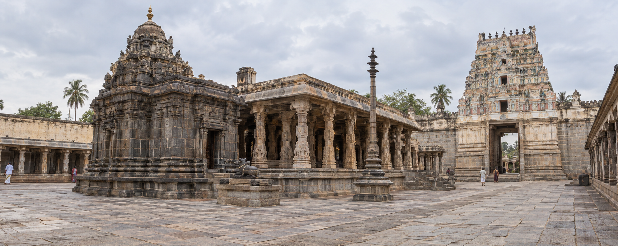 Temple courtyard with a compact granite sanctuary, an added pillared hall, expanded enclosure walls and a later stucco gateway showing different construction phases.